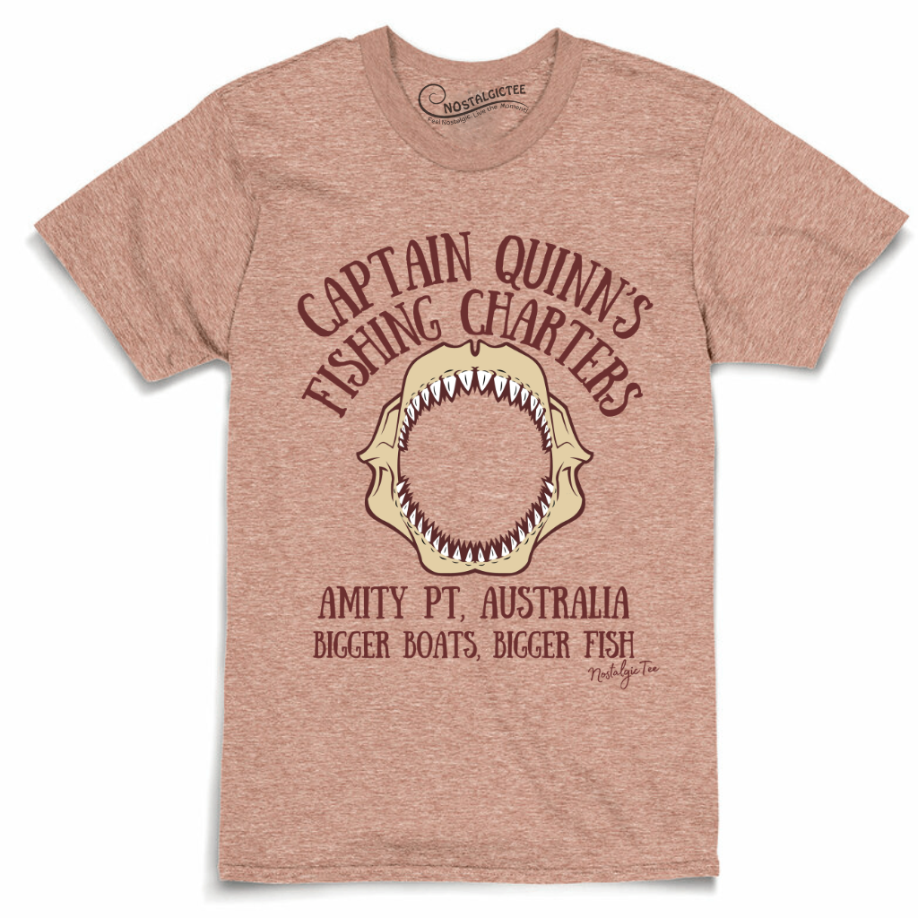 Sunset colored t-shirt featuring a vintage-style graphic of a shark mouth with the text 'CAPTAIN QUINN'S FISHING CHARTERS' and 'AMITY PT, AUSTRALIA BIGGER BOATS, BIGGER FISH'.