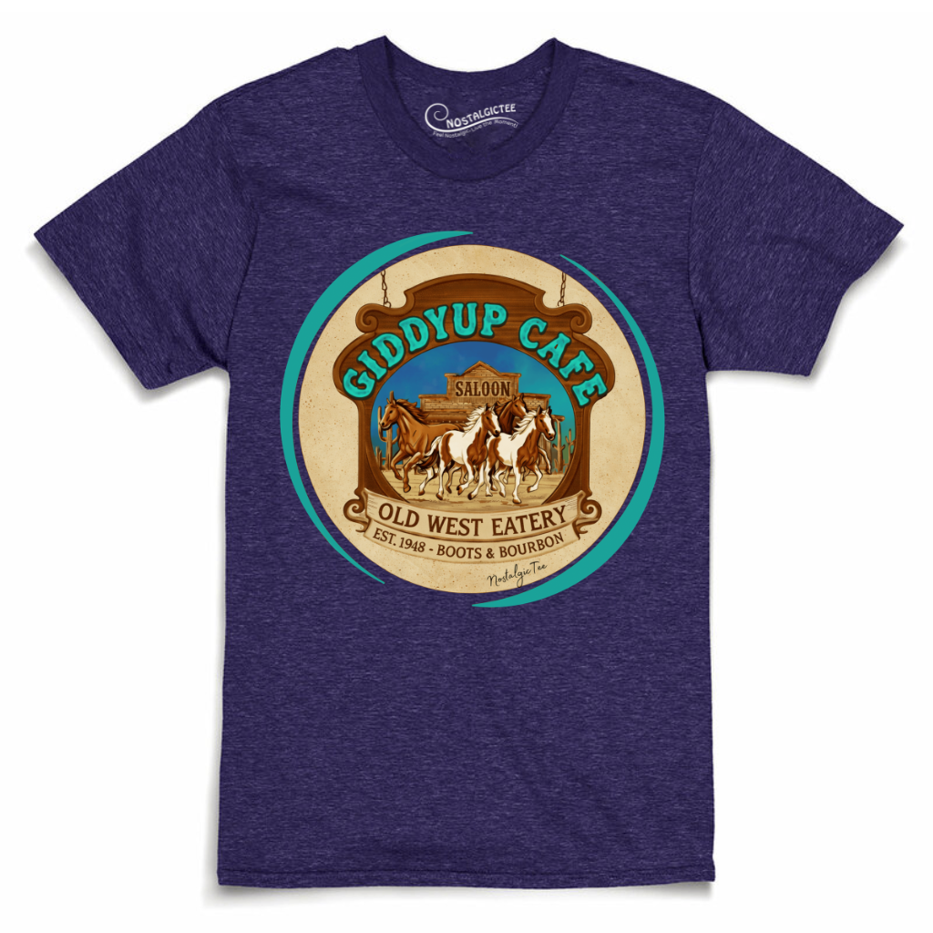 A heather purple short-sleeve t-shirt with a large circular vintage-style graphic on the chest reading 'GIDDYUP CAFE' and 'OLD WEST EATERY' with illustrations of horses and a saloon interior.