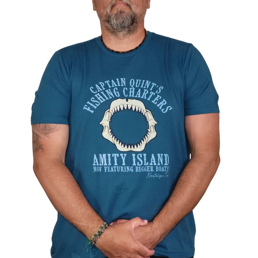 Man wearing a blue t-shirt with a shark tooth graphic and text.