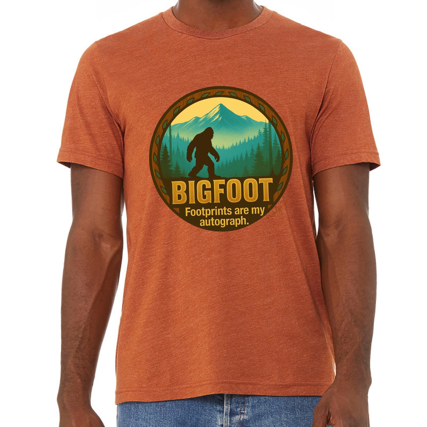 Person wearing an orange t-shirt with a Bigfoot graphic and text.